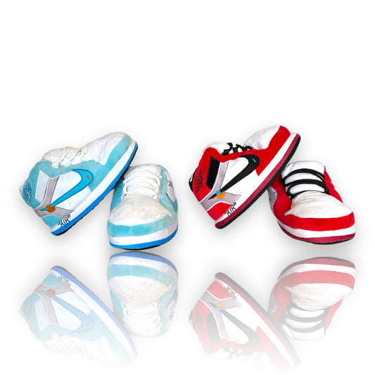 OG AIR Sneaker Slippers – plush sneaker-inspired house shoes in red and baby blue variants shown side by side on reflective white background.